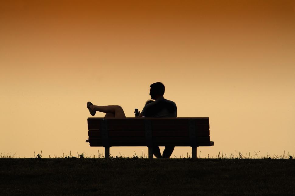 Free Image of Silhouette of person sitting on bench at dusk 