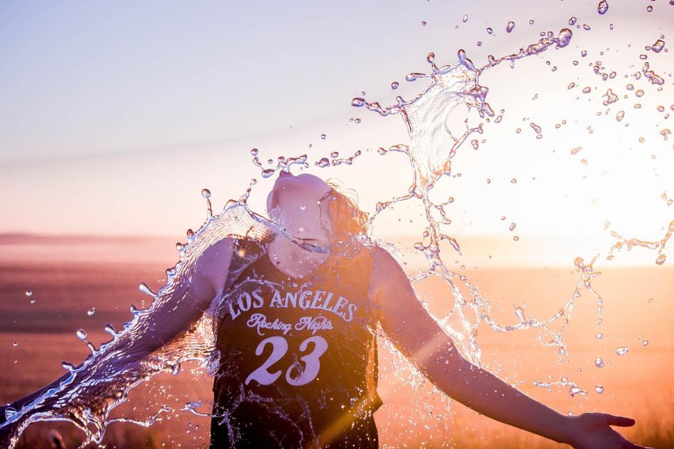 Free Image of Woman splashed by water at sunset 