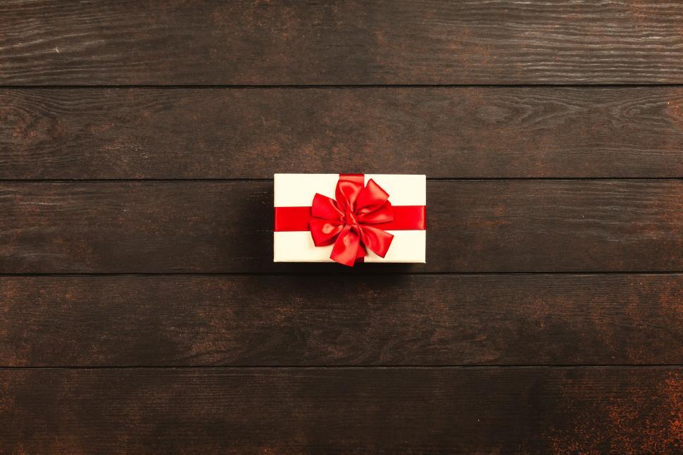 Free Image of Gift box with red ribbon on wooden backdrop 