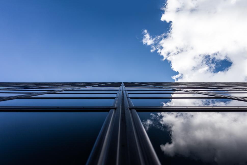 Free Image of Looking up at skyscraper with cloudy sky 