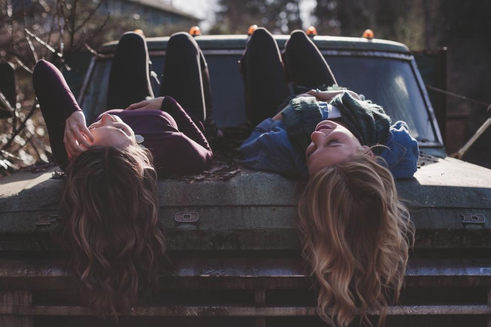 Free Image of Friends lying on an old car laughing 