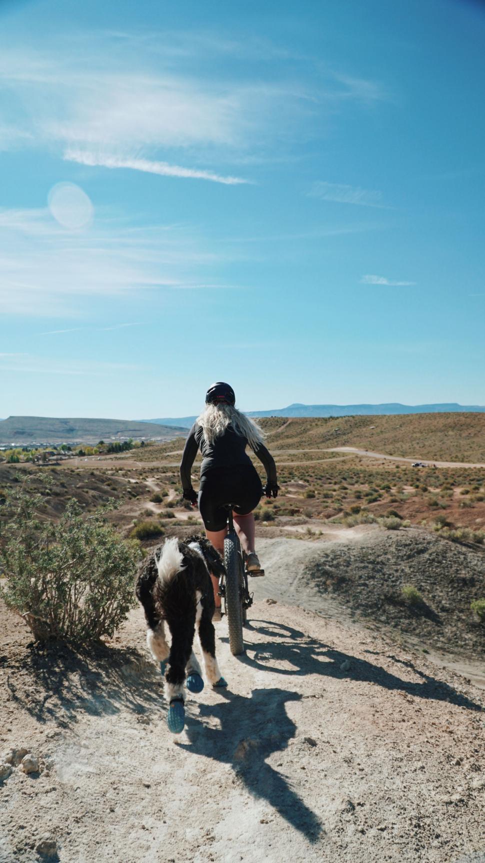 Free Image of Cyclist and dog on a desert trail 