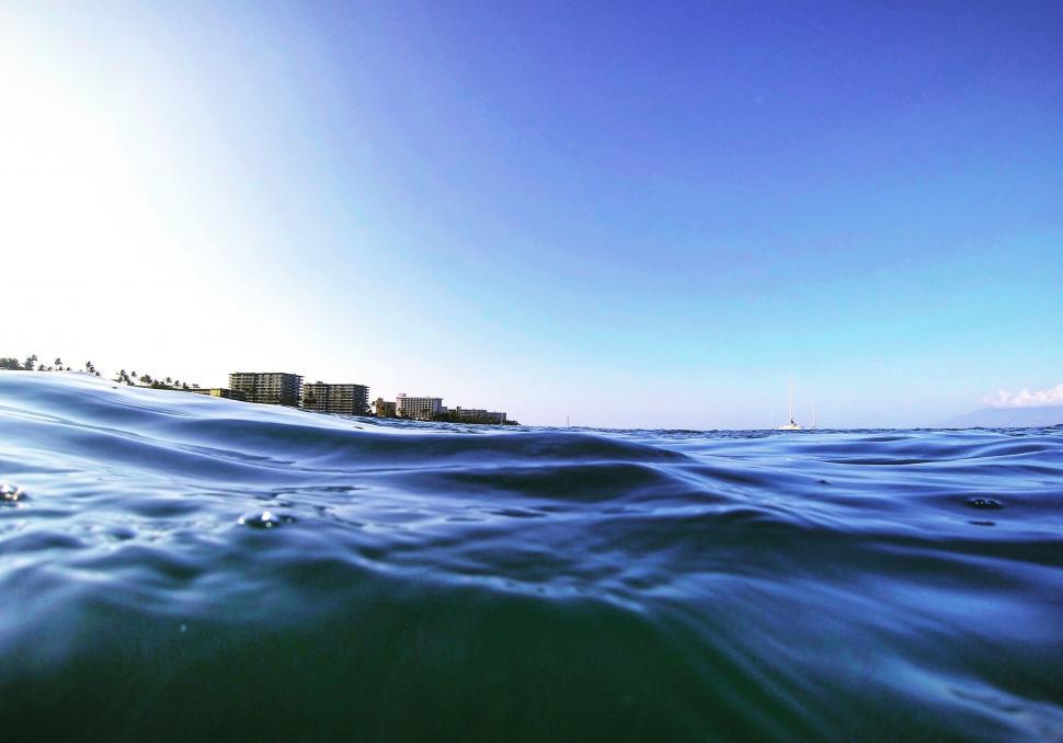 Free Image of Ocean wave with buildings on the horizon 
