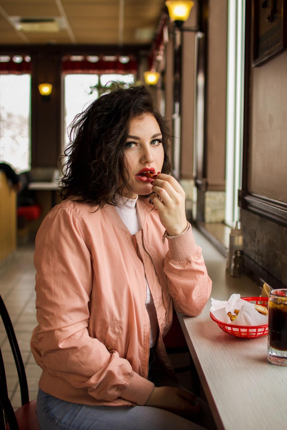 Free Image of Woman eating in a vintage diner setting 