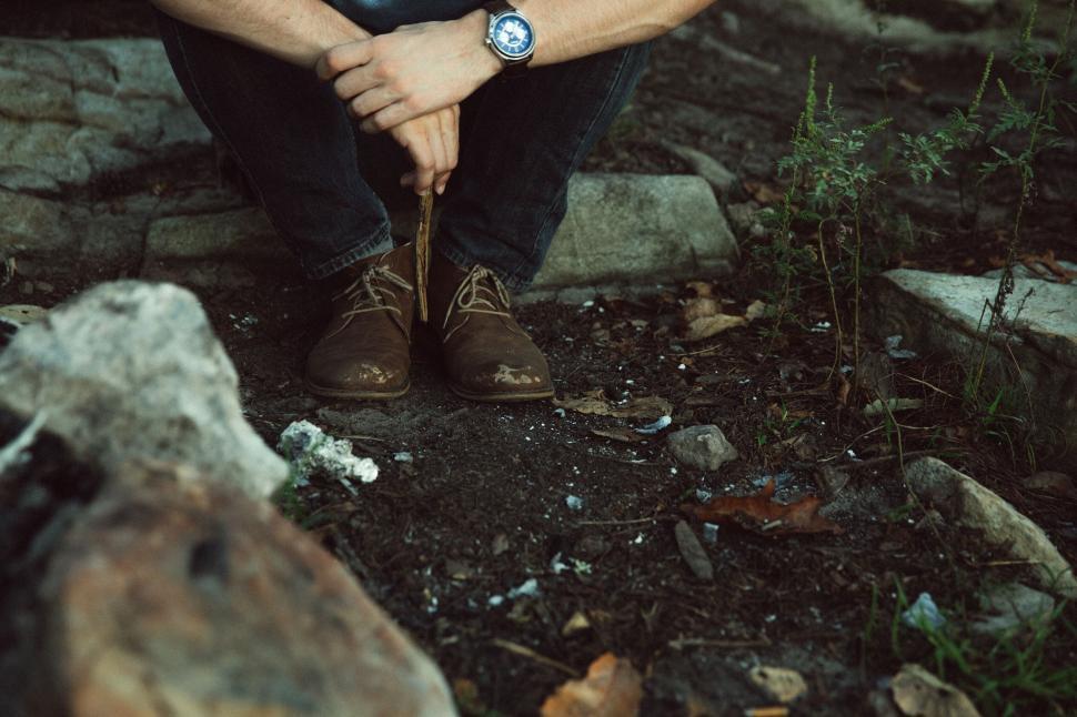 Free Image of Man sitting outdoors with focus on shoes 