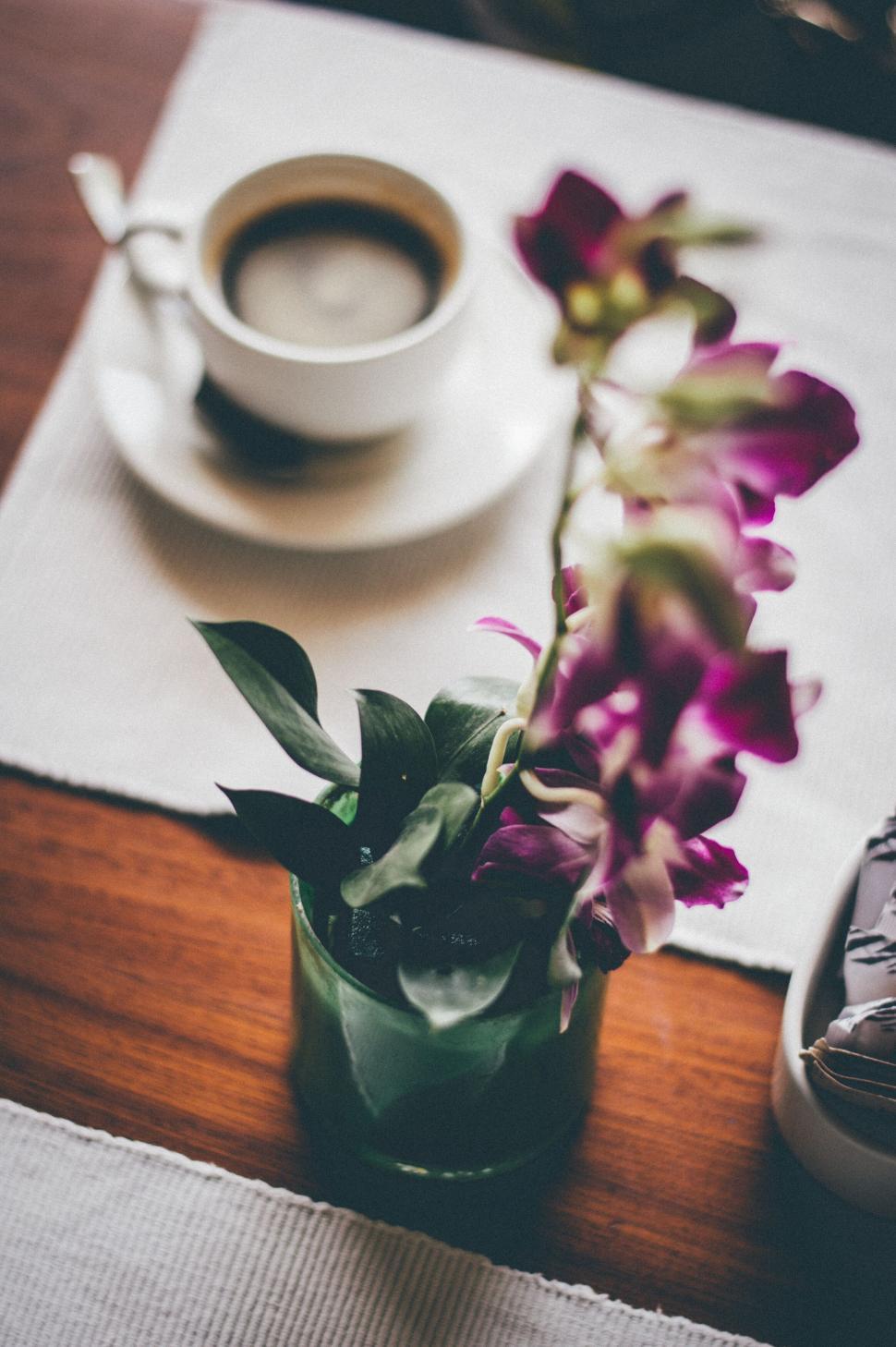 Free Image of Cup of coffee with fresh orchids on table 