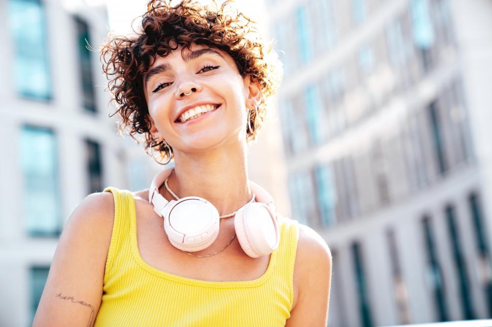 Free Image of A woman with curly hair wearing headphones around her neck 