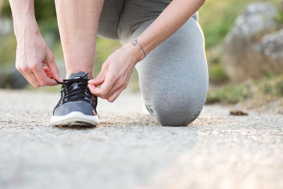 Free Image of Person tying running shoes on a path 