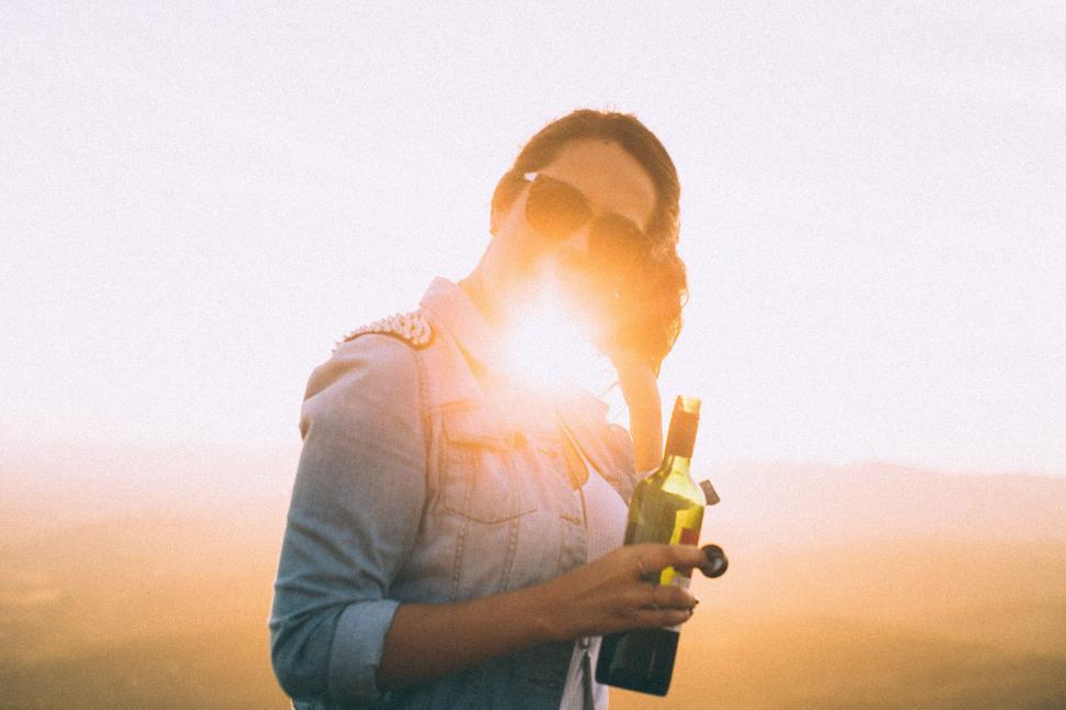 Free Image of Person holding wine bottle at sunset 