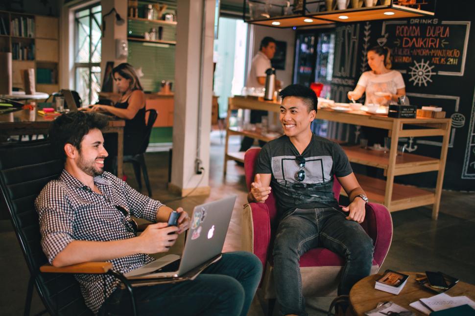 Free Image of Men in coffee shop on laptops laughing 