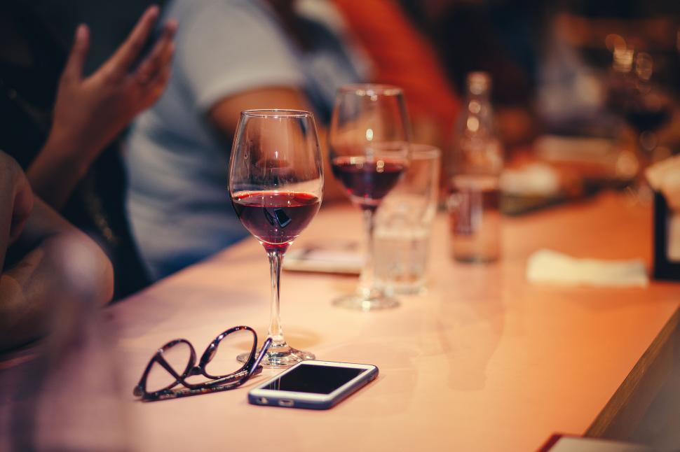 Free Image of Glass of red wine on a table with phone 