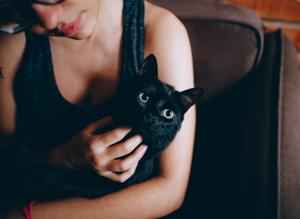 Free Image of Woman holding a black cat closely 