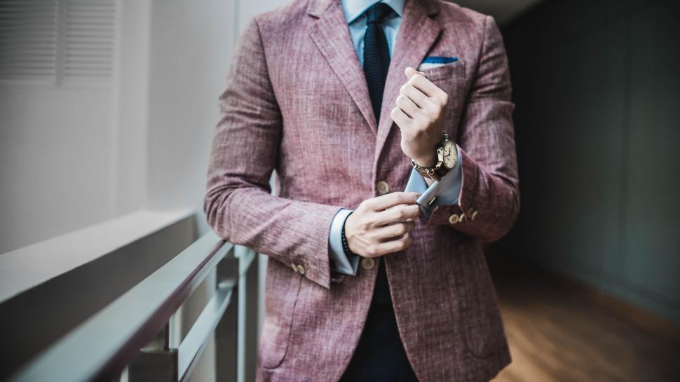 Free Image of Stylish man in pink suit adjusting watch 