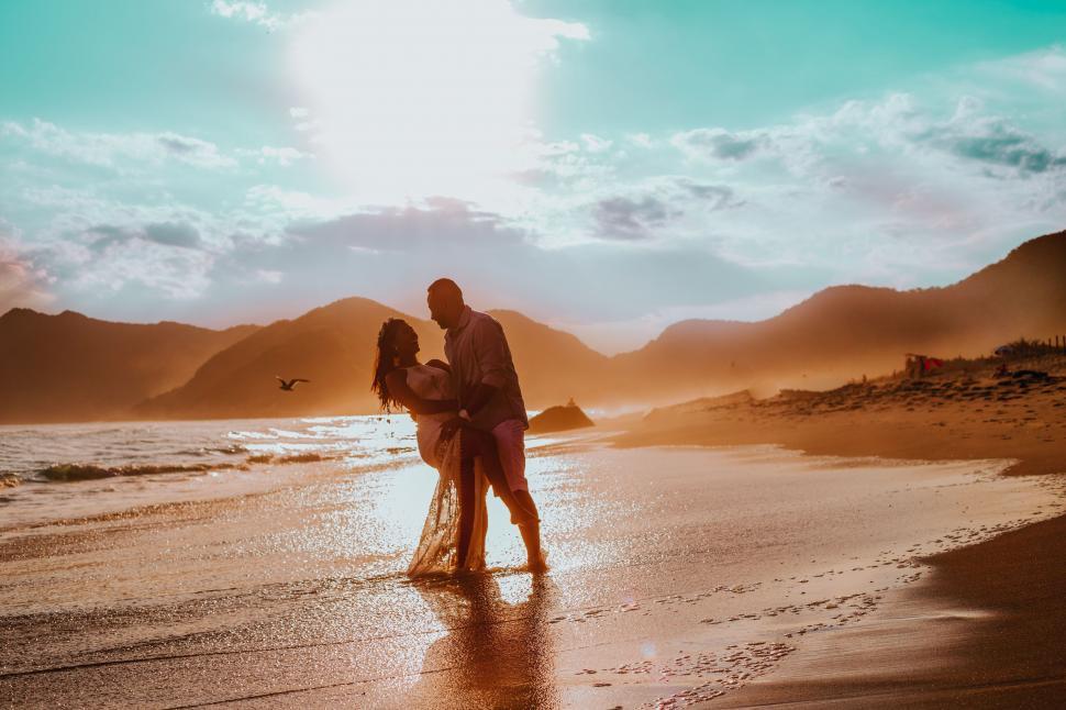 Free Image of Couple embracing on a beach at sunset 