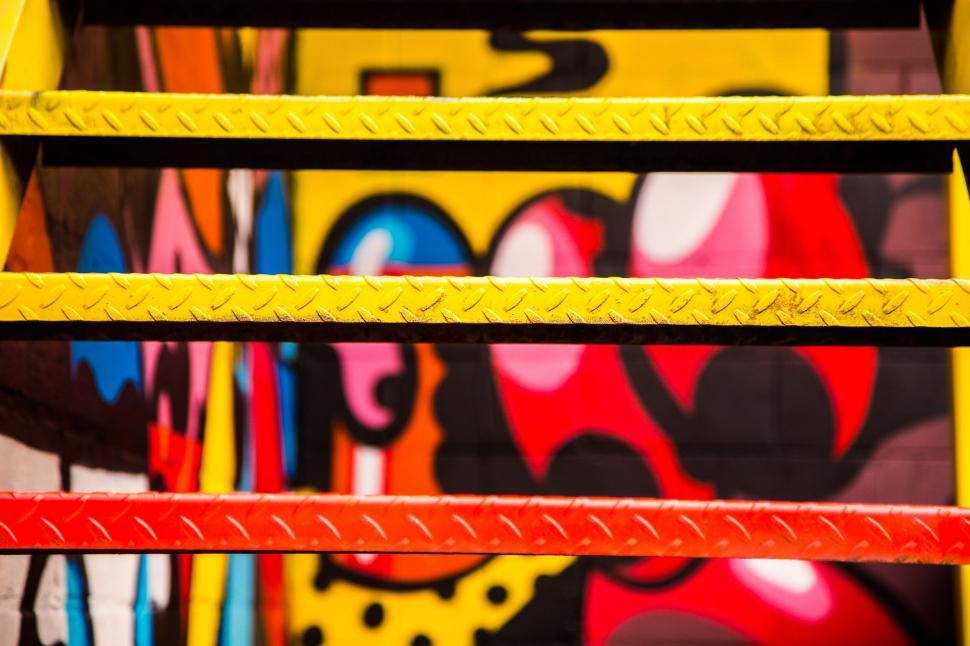 Free Image of Colorful urban art and yellow metal bars 