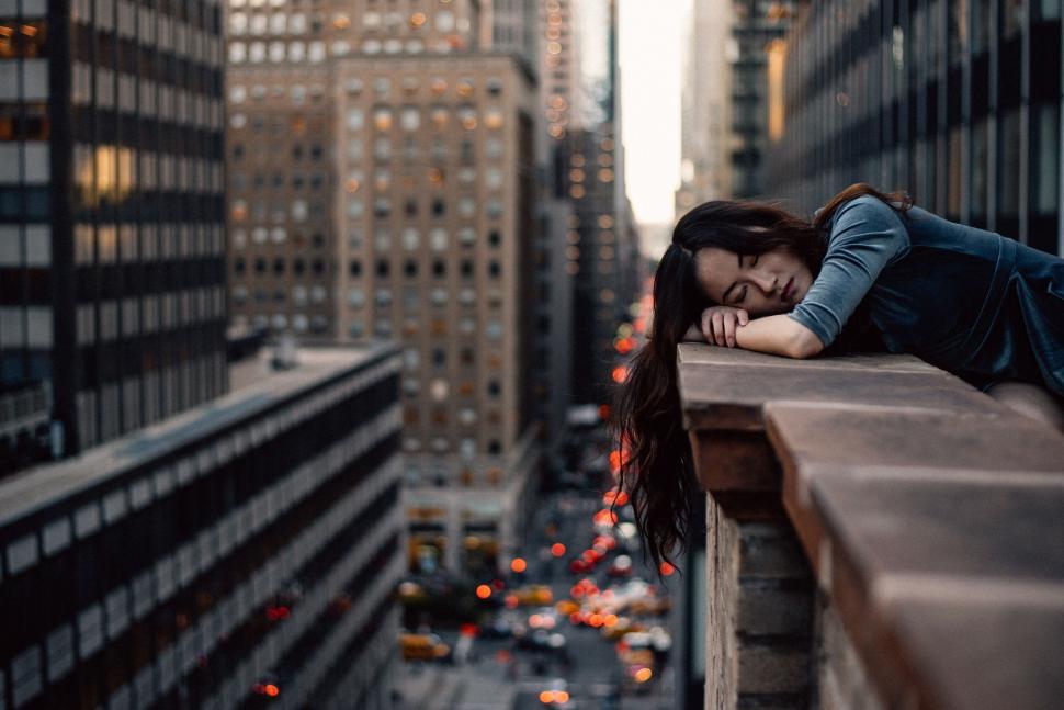 Free Image of Person leaning on a ledge over a city street 