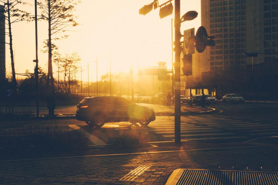 Free Image of Car driving through city intersection at sunset 