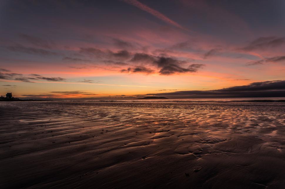 Free Image of Sunset with dramatic sky on a sandy beach coast 