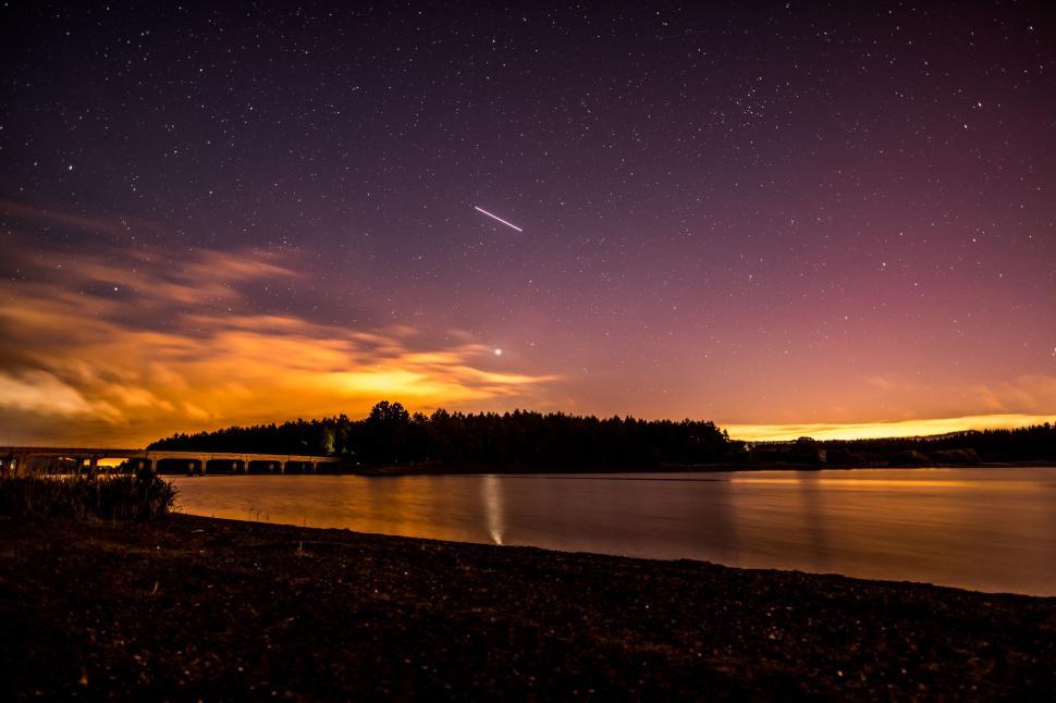 Free Image of Night sky with shooting star over a lakeshore 