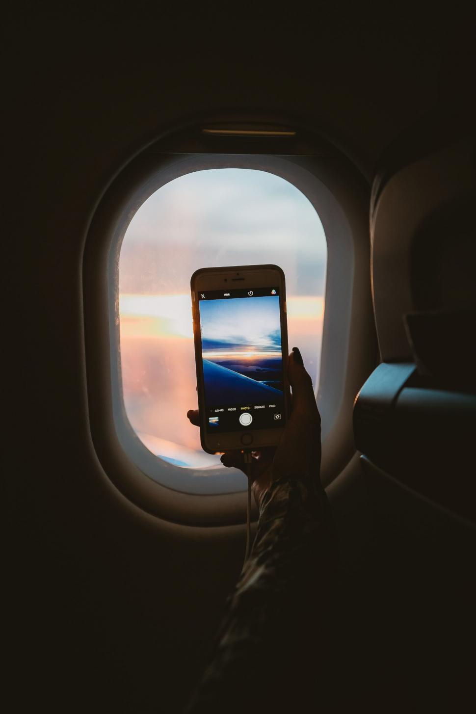 Free Image of Capturing the sunset through smartphone on a plane 