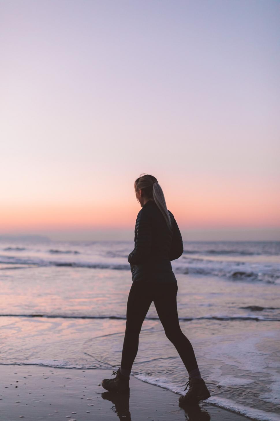 Free Image of Woman walking on beach at sunset 