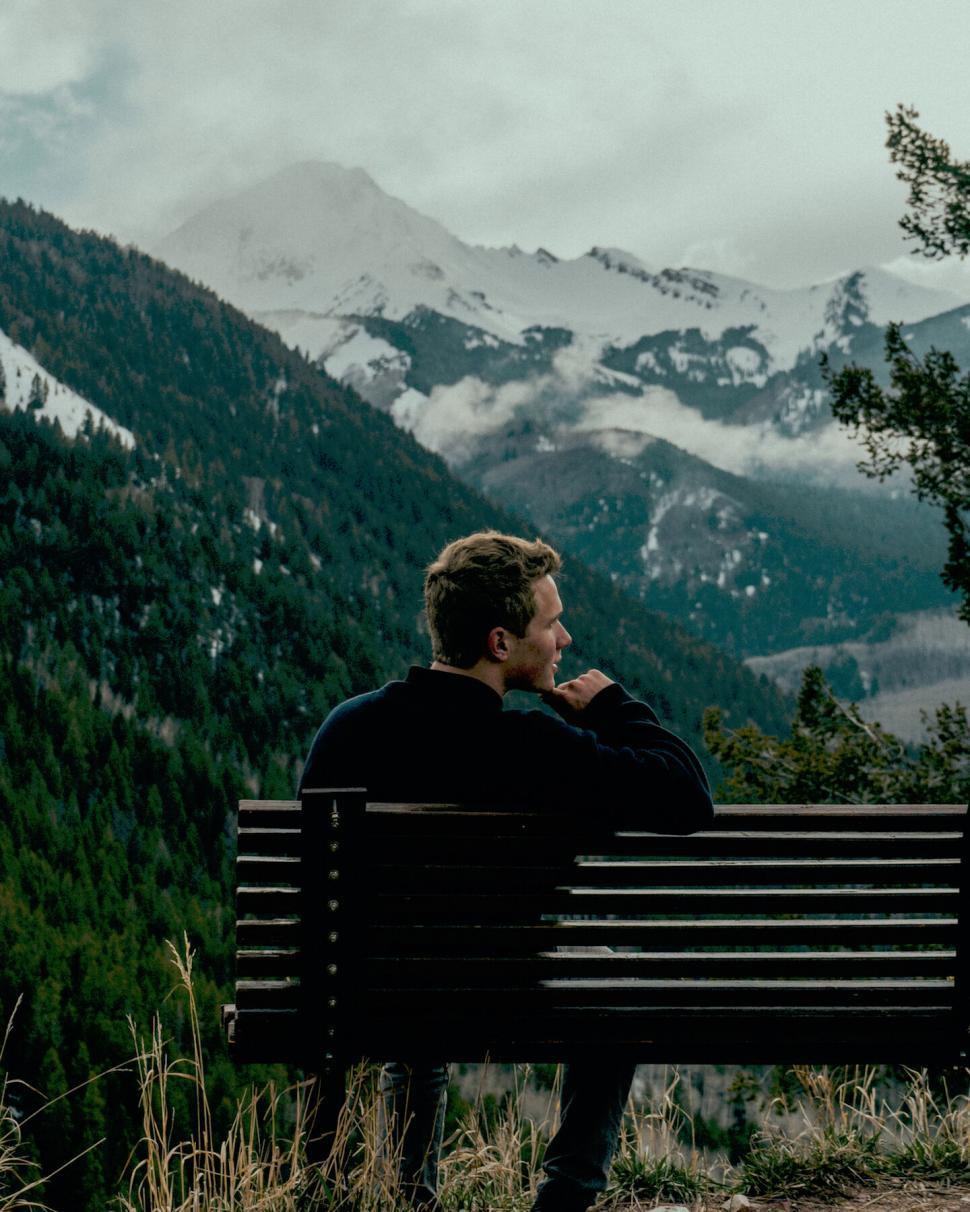 Free Image of Person sitting on bench facing mountains 
