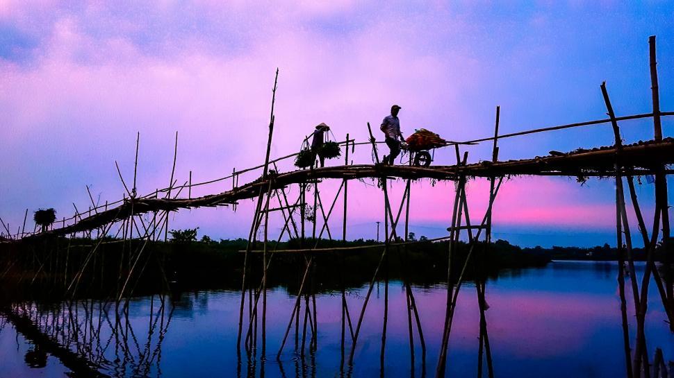 Free Image of People crossing bamboo bridge at dusk 