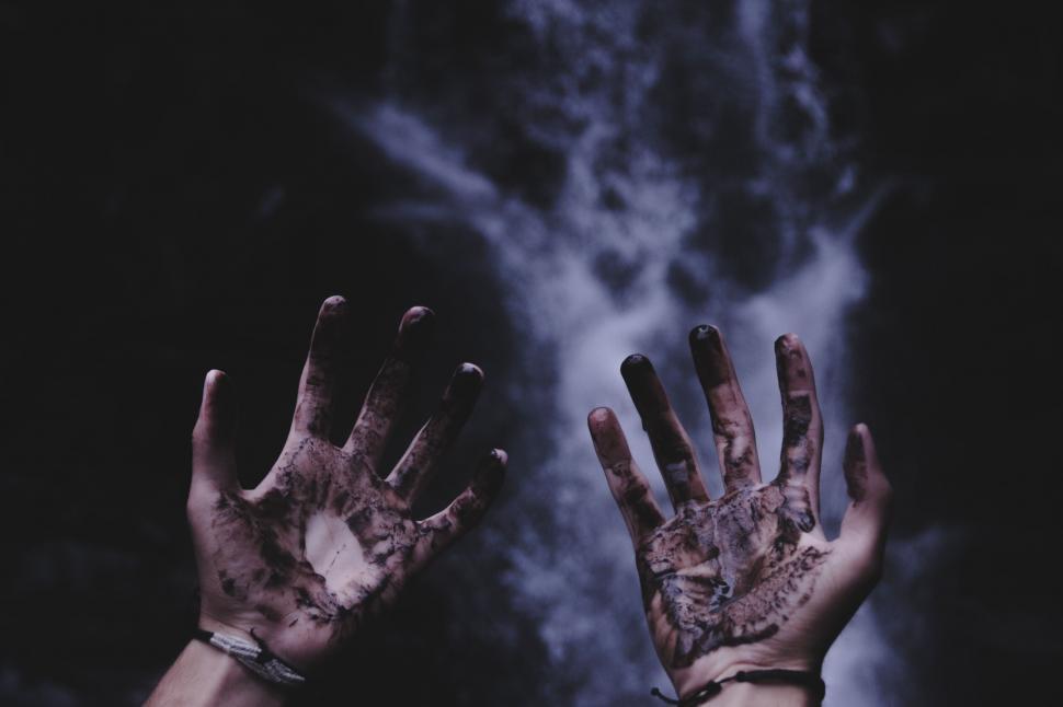 Free Image of Muddy hands raised up with waterfall 