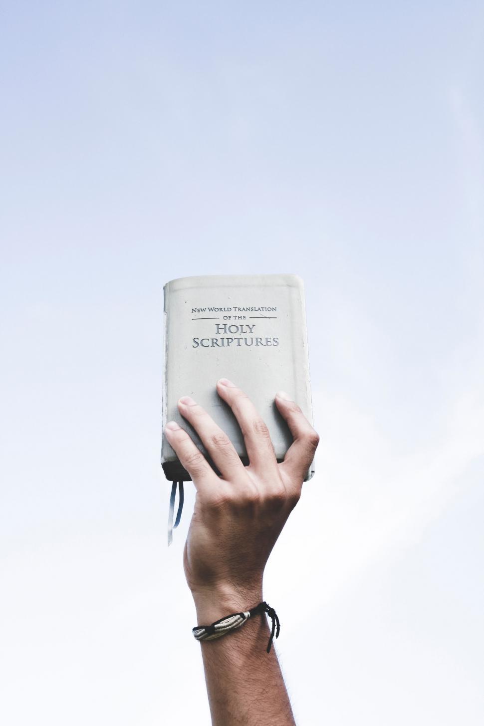 Free Image of Hand Holding a Holy Book Against Sky 