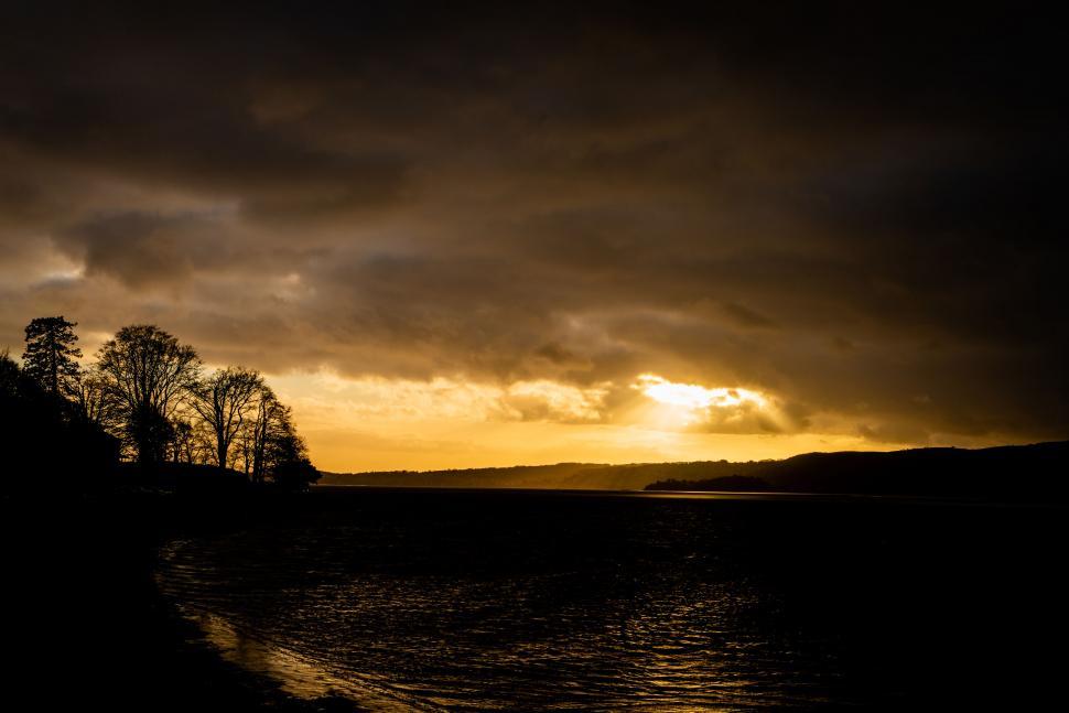 Free Image of Dramatic sunset over a lake with trees 