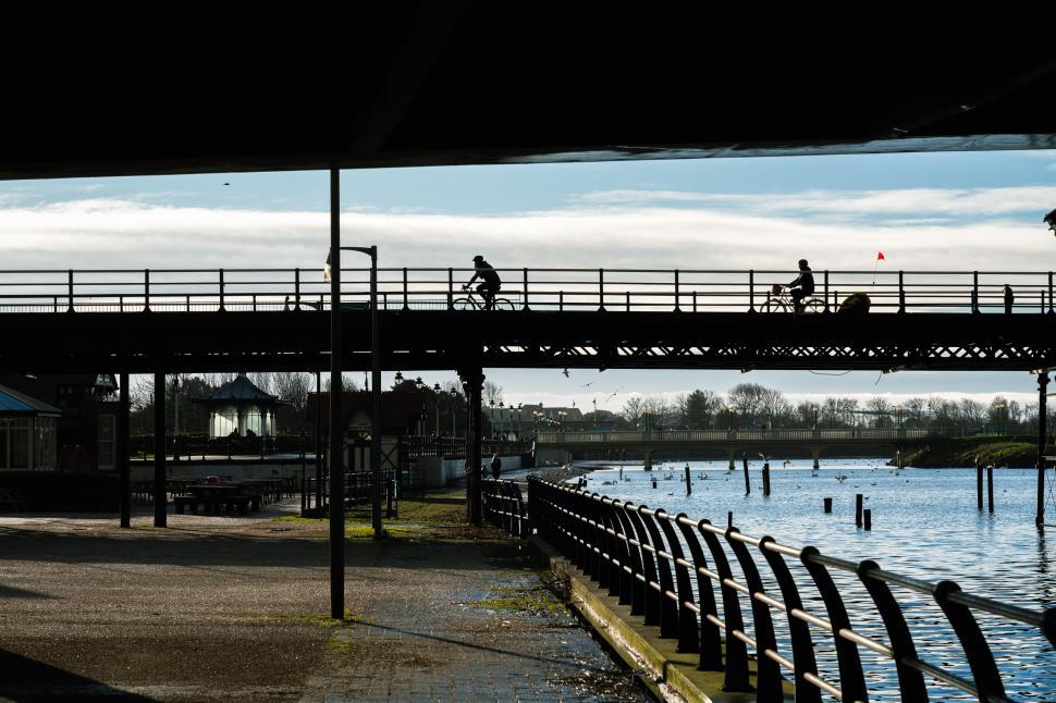 Free Image of Cyclists crossing a bridge silhouette 