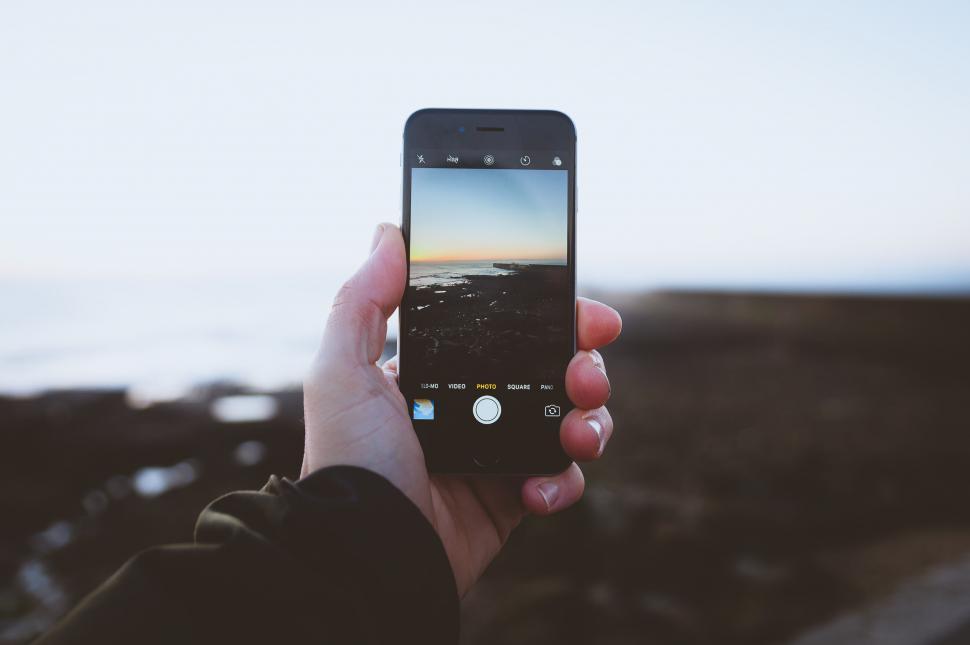 Free Image of Hand holding smartphone showing seascape on screen 