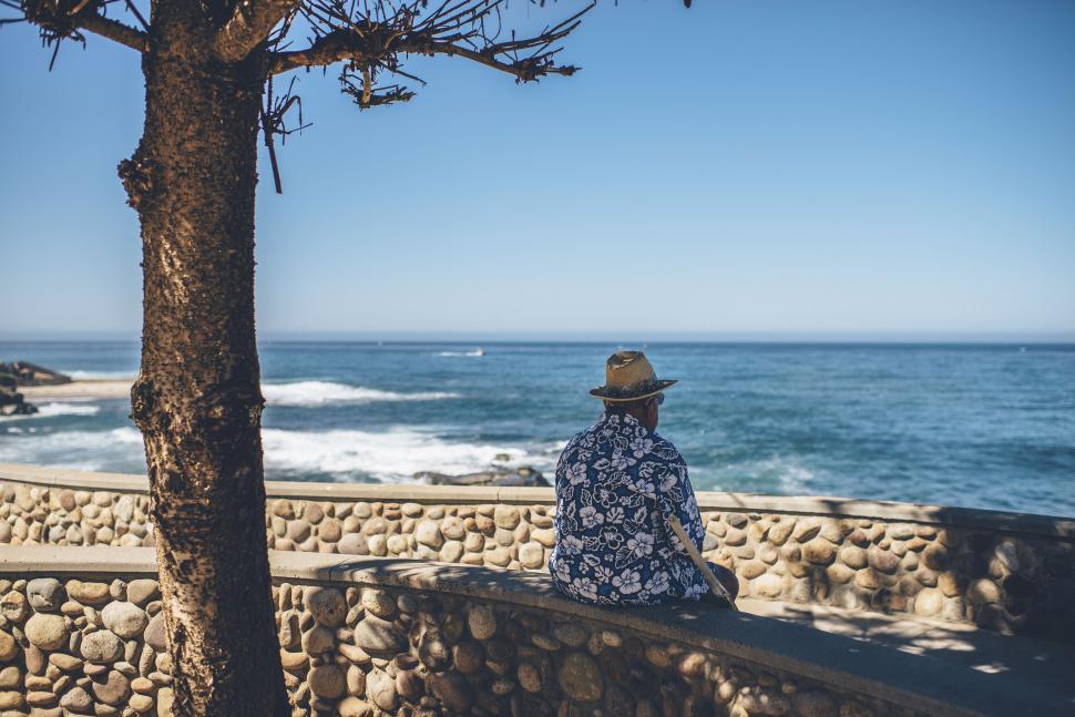 Free Image of Person sitting by the ocean looking out at sea 