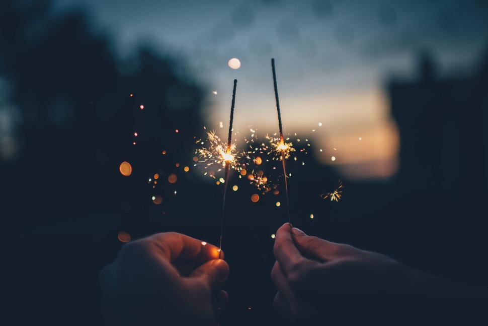 Free Image of Hands holding sparklers at dusk 