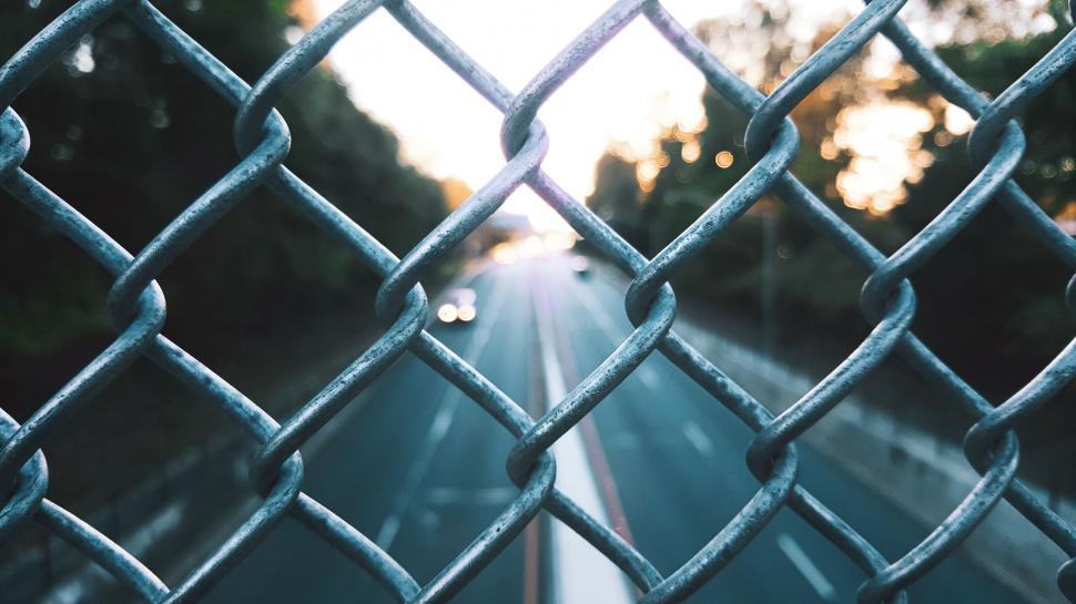 Free Image of Chain-link fence with blurred street background 