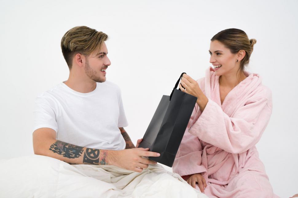 Free Image of Happy couple exchanging gifts in bed 