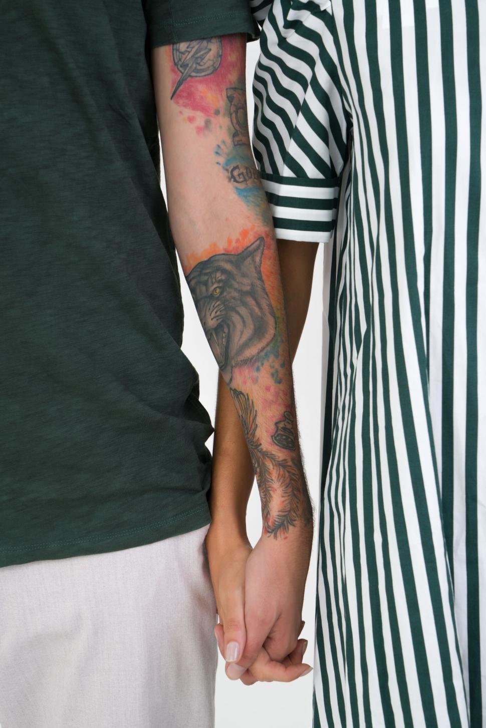 Free Image of Two people holding hands showcasing arm tattoos 