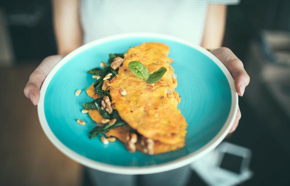 Free Image of Person holding a plate of omelet and greens 