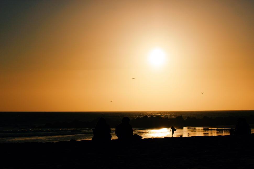 Free Image of Beach sunset with silhouetted figures 