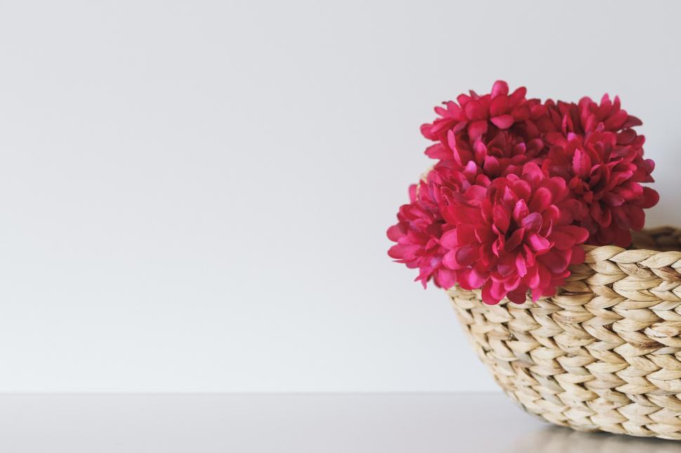 Free Image of Vibrant red flowers in a wicker basket 