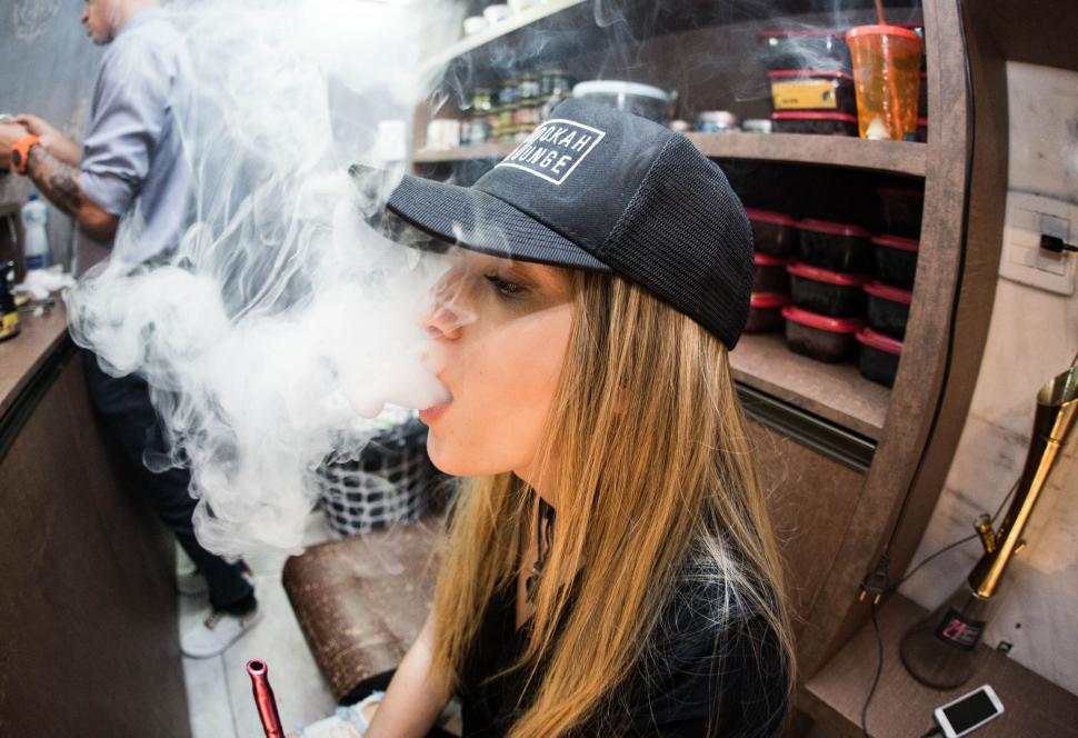 Free Image of Energetic woman exhaling vapor in a cap 