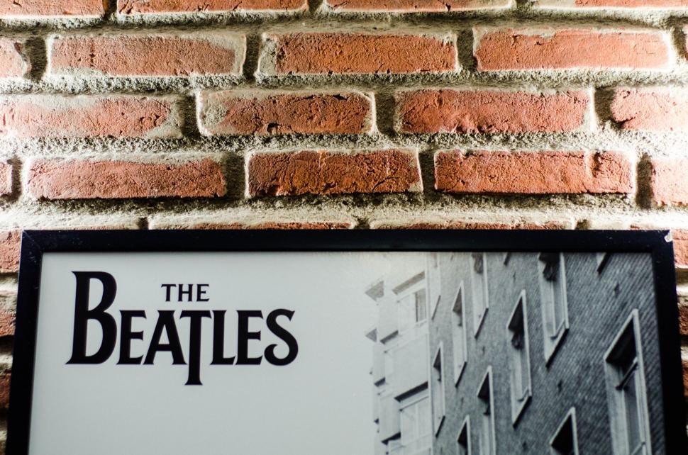 Free Image of Framed Beatles poster on a brick wall 