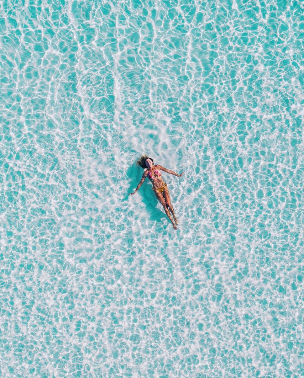 Free Image of Woman floating in clear turquoise water 