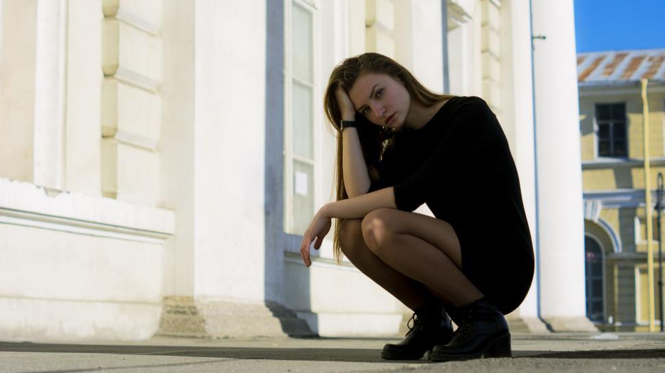 Free Image of Woman in black sitting on curb 