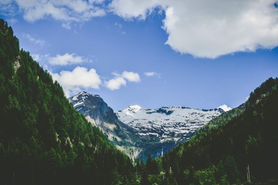 Free Image of Snowy mountain peak above forested hills 