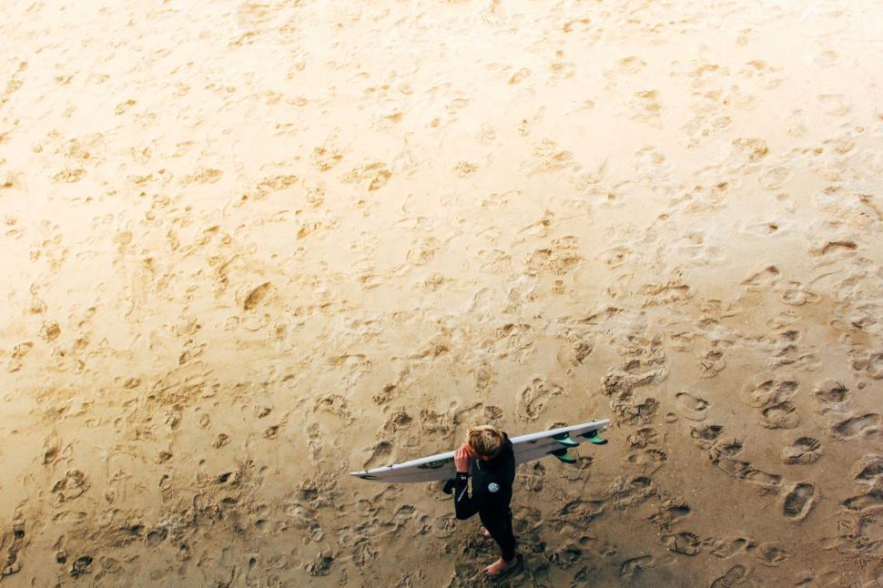 Free Image of Surfer walking on sandy beach 