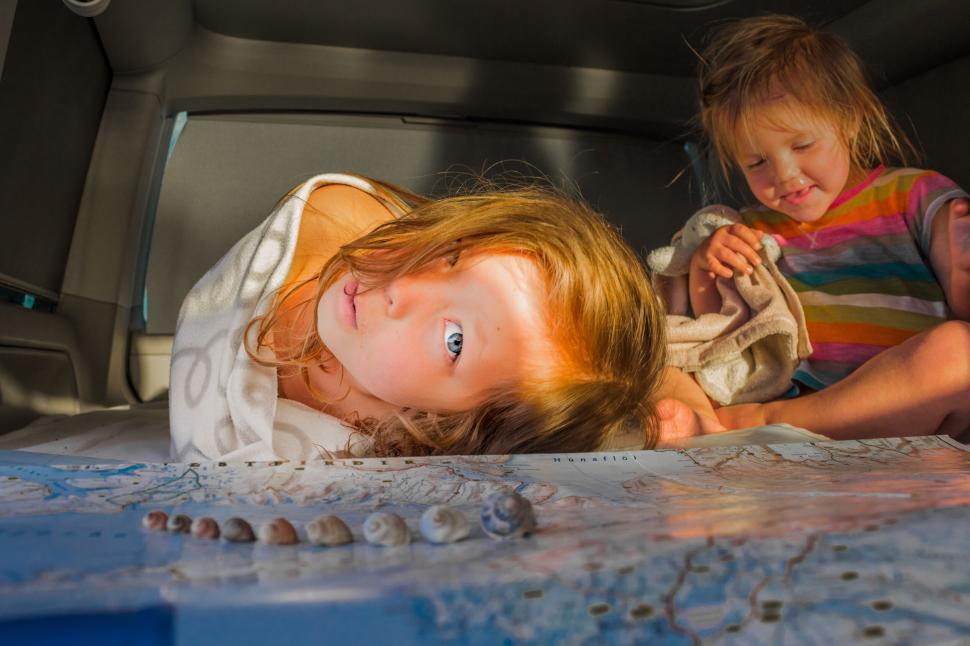Free Image of Children playing with a map in a car 