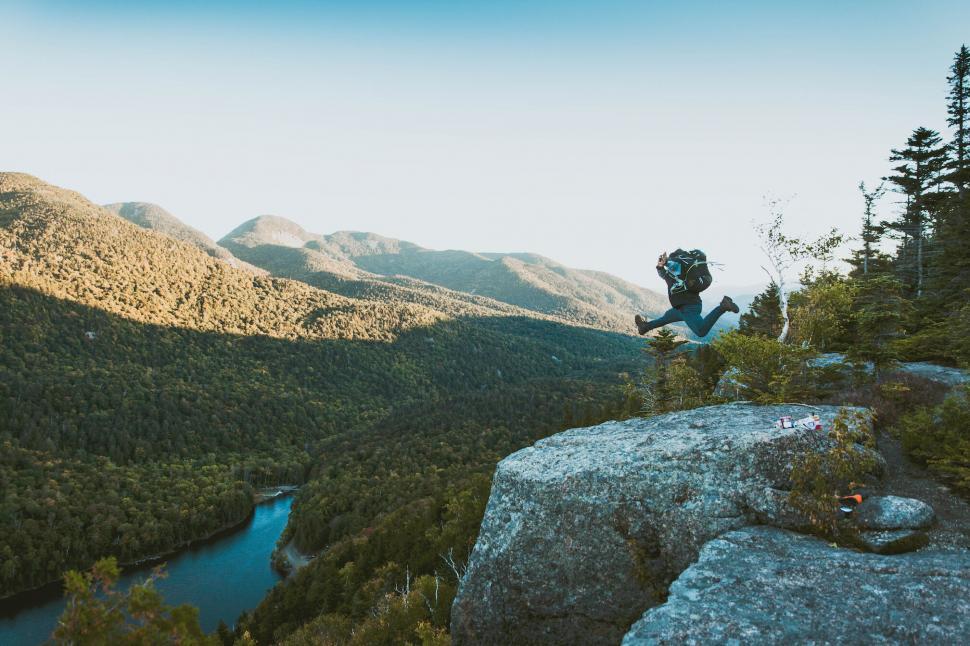 Free Image of Hiker jumping above a scenic valley 