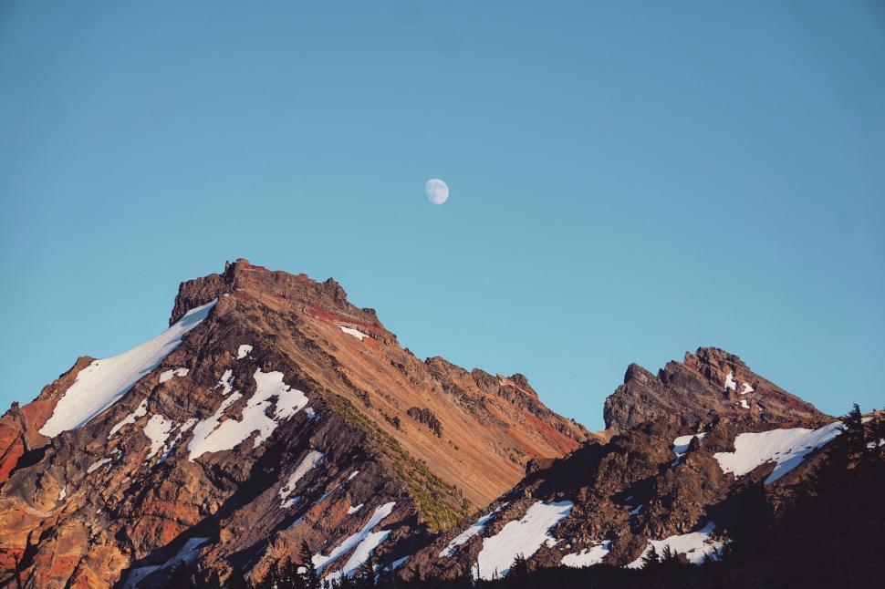 Free Image of Moon over rugged mountain peak at dusk 