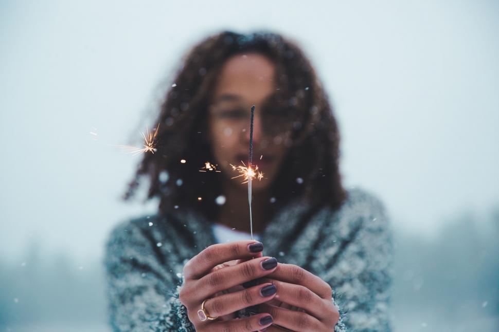 Free Image of Woman holding a lit sparkler in snow 